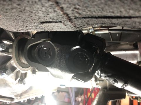 1992 Jeep Wrangler - A close-up view shows the driveshaft and universal joint connected to a vehicle's transmission or transfer case. The metal components are b…
