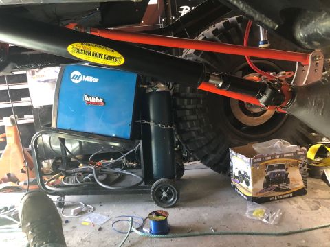 1992 Jeep Wrangler - A black custom drive shaft with a yellow "Tom Wood's Custom Drive Shafts" sticker is visible above a blue Miller "Bank's Power" welding mac…