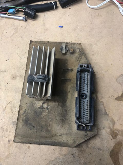 1992 Jeep Wrangler - A close-up view shows a black multi-pin connector and a silver heatsink mounted on a dirty, cracked board. The components appear to be part…