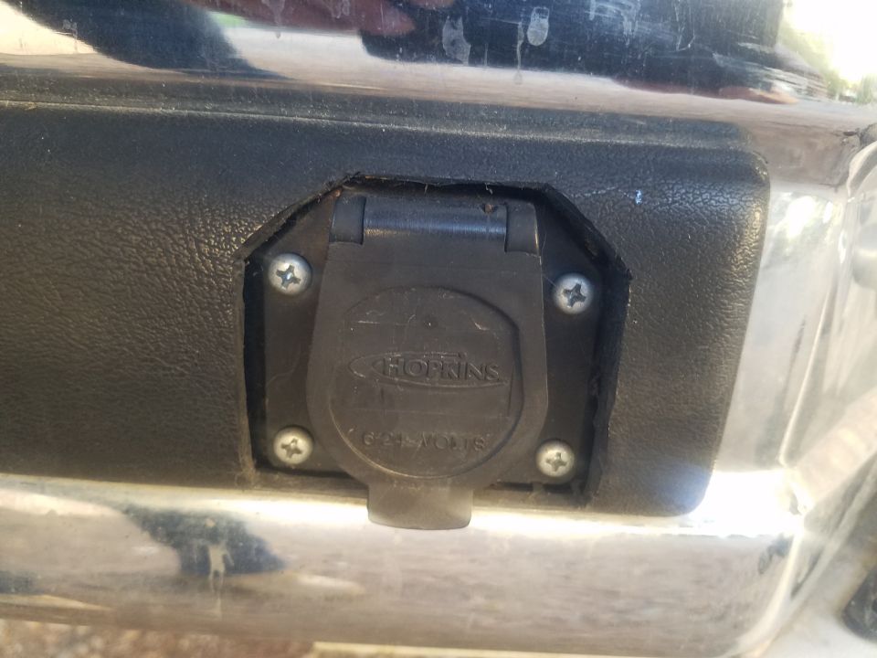 Close-up of a Hopkins 7-way trailer connector on a vehicle's chrome bumper.