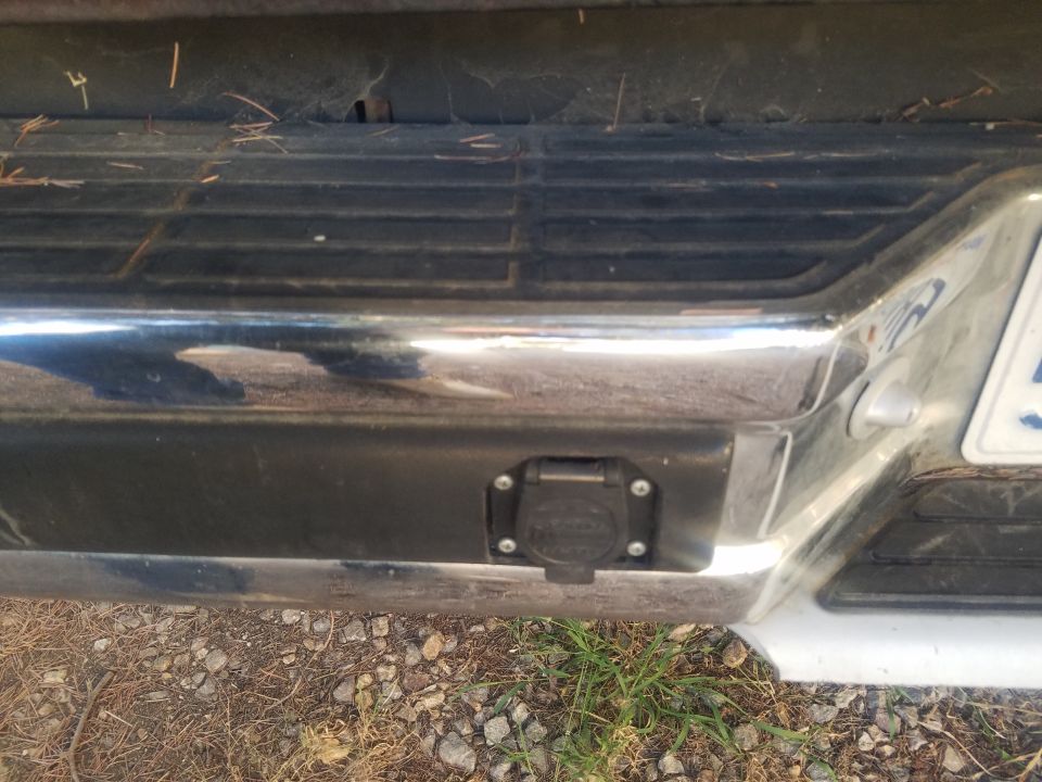 Close-up of a black trailer hitch connector on a vehicle's rear bumper.
