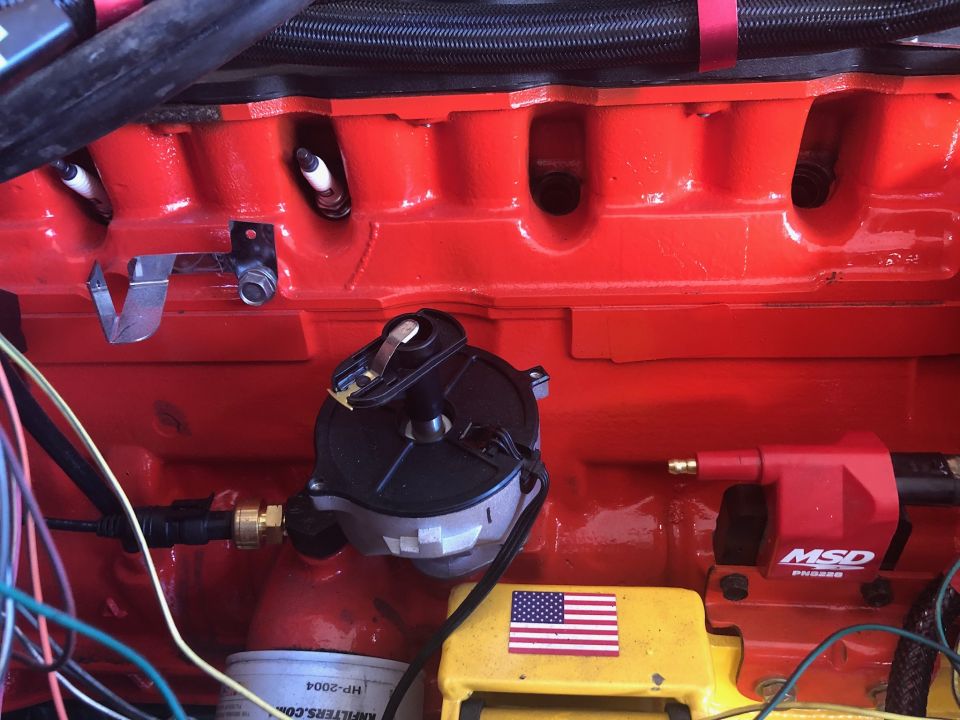 Red engine block with spark plugs, distributor, MSD coil, and wires.