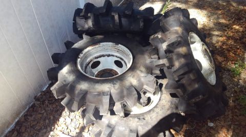 1988 Ford Bronco - A stack of three large, worn tractor tires with aggressive treads and white rims are piled on the ground next to a light-colored wall. The…