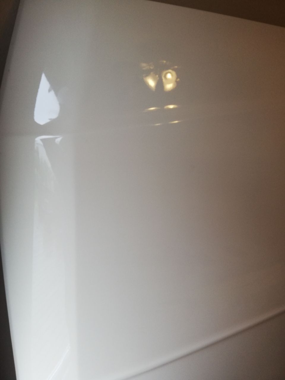 Glossy white vehicle exterior with reflections of lights.
