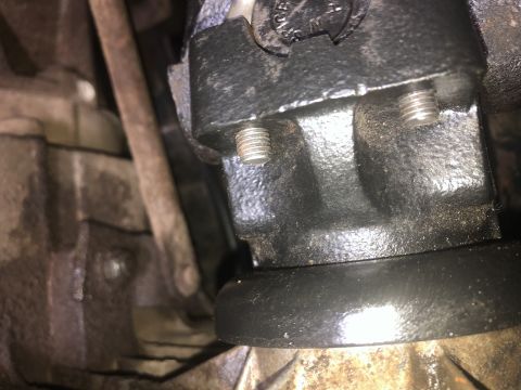1980 Ford Bronco - A close-up view shows two silver bolts threaded into a black metal component, likely part of a vehicle's drivetrain. The surrounding area i…