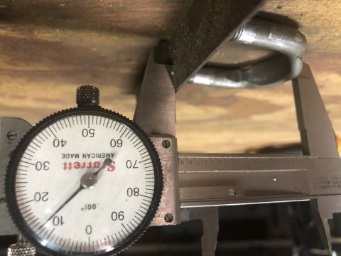 1980 Ford Bronco - A dial caliper measures the diameter of a metal U-shaped shackle against a wooden surface.