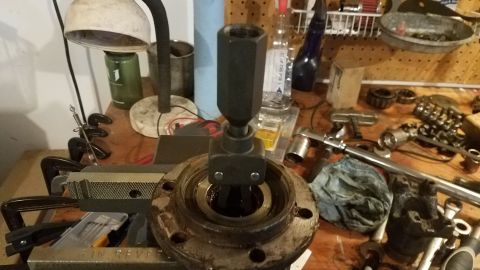 1985 Ford Bronco - A bearing separator tool is being used on a rusty hub assembly that is clamped in a vise. Various tools and parts are scattered on the work…