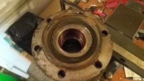1985 Ford Bronco - A close-up, overhead view of a metal component with a circular opening. The component has a flange with four bolt holes and appears to be g…
