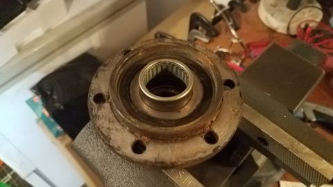 1985 Ford Bronco - A close-up, slightly angled view of a rusty metal automotive part, possibly a hub or bearing assembly, is clamped in a vise. The part has s…