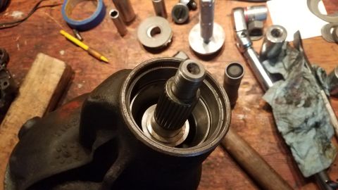 1985 Ford Bronco - A close-up view of a disassembled steering gear box with a splined shaft protruding from the housing. Various tools and parts are scattered…