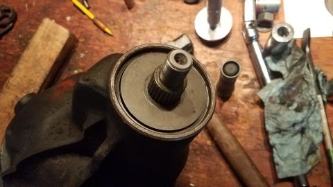 1985 Ford Bronco - A close-up view of a splined shaft protruding from a black, cast-iron automotive steering gear housing. Tools and a rag are visible on the…