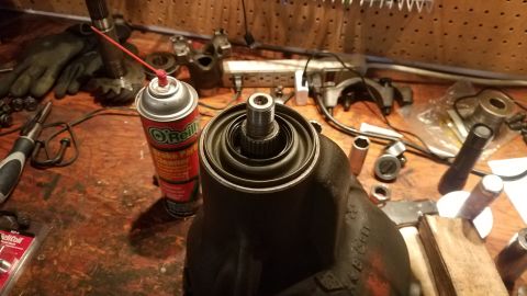1985 Ford Bronco - A close-up view of a differential housing with a splined shaft protruding from the top, surrounded by various tools and a can of O'Reilly B…