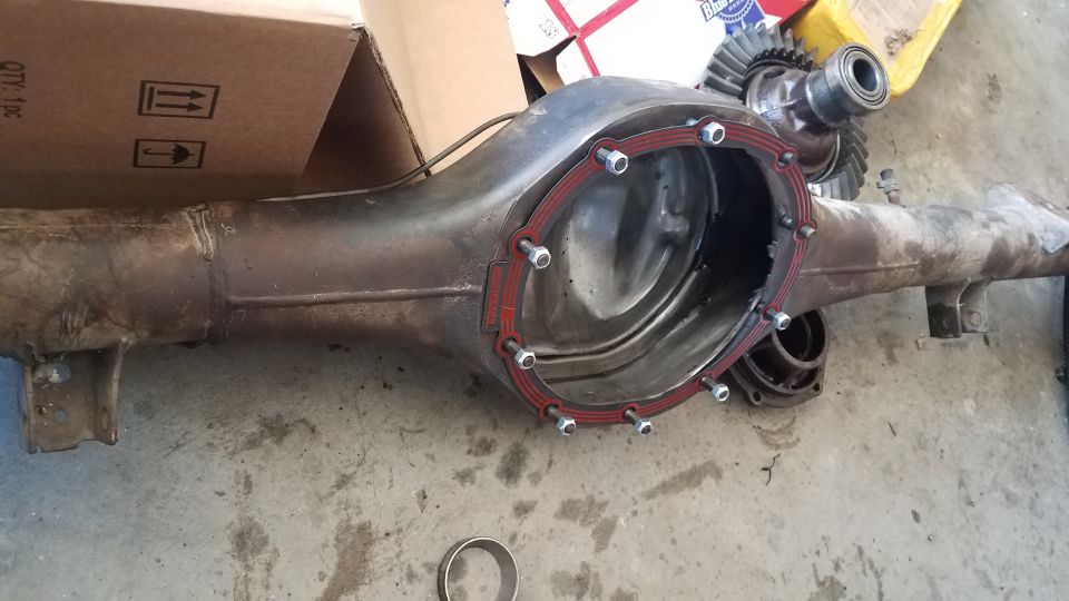 Differential housing with red gasket and bolts, ring gear and pinion gear.