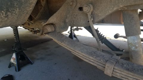 1985 Ford Bronco - The underside of a vehicle, likely a 1985 Ford Bronco, is shown supported by jack stands. A leaf spring suspension system is visible, along…