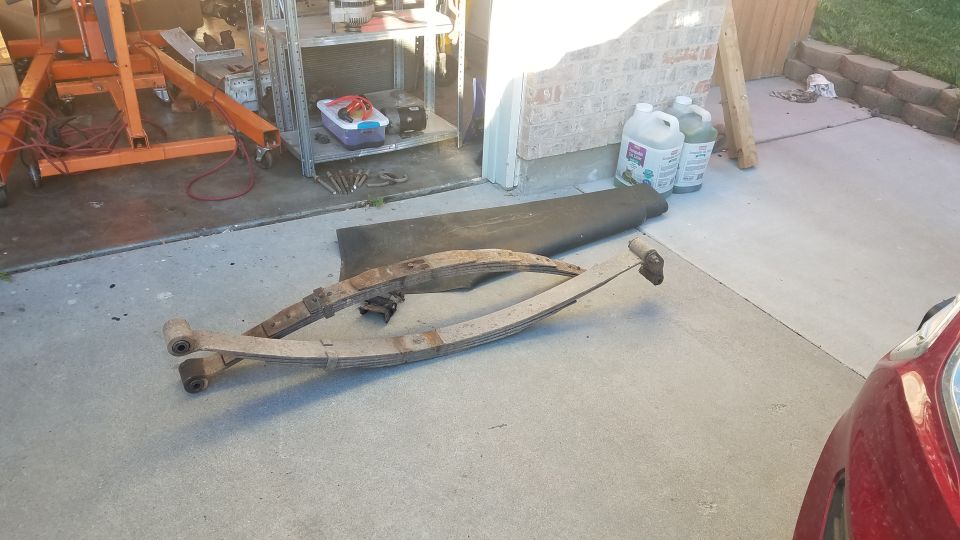 Two rusty leaf springs on a concrete driveway.