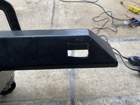 1994 Ford Bronco - A black bumper part with cutouts sits on a dolly, with electrical cords and a tool visible in the background.