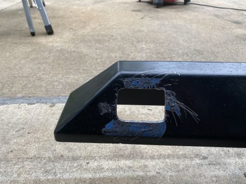 1994 Ford Bronco - Close-up of a black bumper section showing a cut-out and signs of wear and tear.