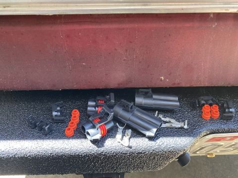 1994 Ford Bronco - Various electrical connectors and orange seals are laid out on a textured surface, with a portion of a red vehicle visible.