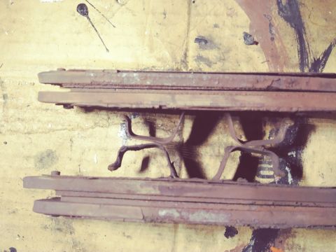 1996 Ford Bronco - Close-up view of two worn brake pads, showing a star-shaped spring clip between them.