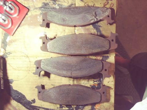 1996 Ford Bronco - Four brake pads are shown on a workbench, with a package of hardware nearby.