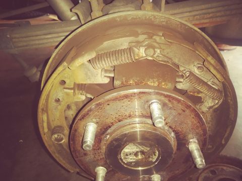 1996 Ford Bronco - Rear drum brake assembly showing wear and tear, with springs and brake shoes exposed.