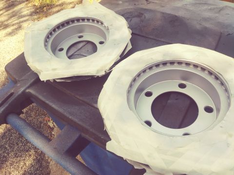 1996 Ford Bronco - Two new brake rotors are prepared for installation, wrapped in masking paper on a stand.