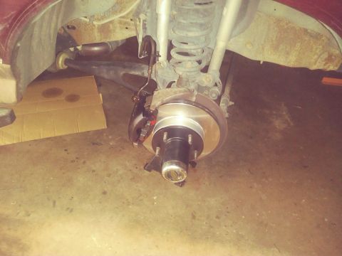 1996 Ford Bronco - Vehicle brake assembly with new rotor and caliper installed in a garage setting.