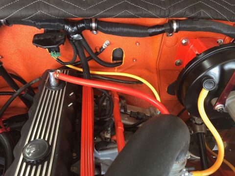 1992 Jeep Wrangler - Close-up view of an engine bay with custom wiring and hoses visible against an orange firewall.