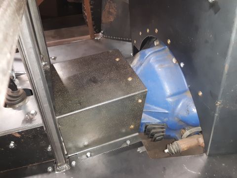 1985 Toyota Hilux - The interior of a vehicle shows the transmission tunnel with a blue transmission and a custom metal cover.