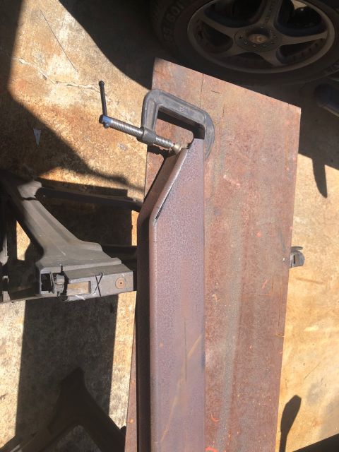 1992 Jeep Wrangler - A metal part is secured with a clamp, positioned on a larger metal sheet for fabrication work.