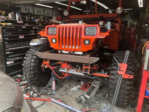 1992 Jeep Wrangler - This modified Jeep Wrangler, likely from the early 1990s, is undergoing work in a cluttered garage.