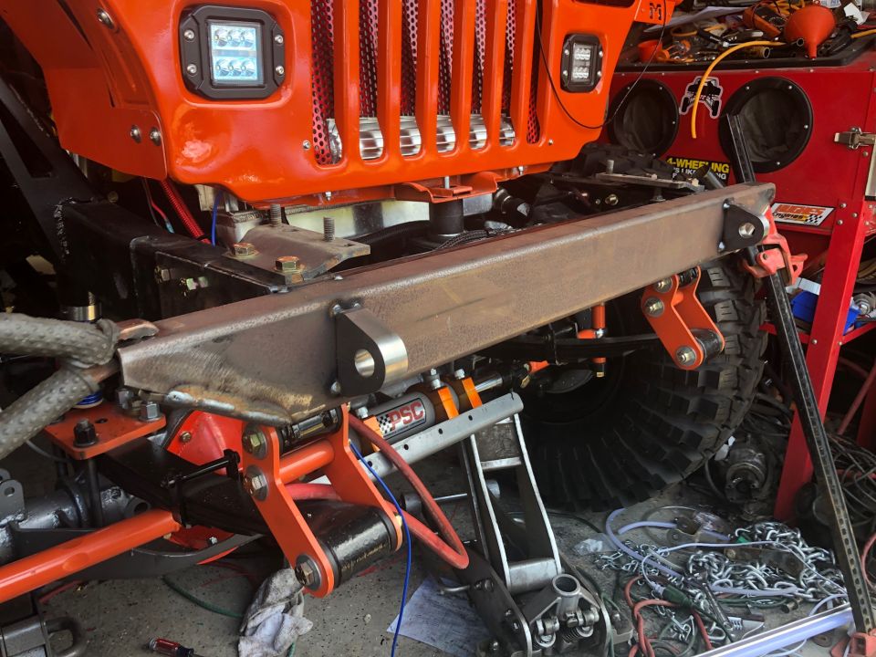 Orange Jeep Wrangler front end, custom bumper installed, suspension parts visible