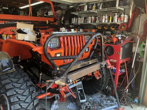 1992 Jeep Wrangler - An orange Jeep Wrangler is partially visible in a cluttered garage, undergoing modifications.
