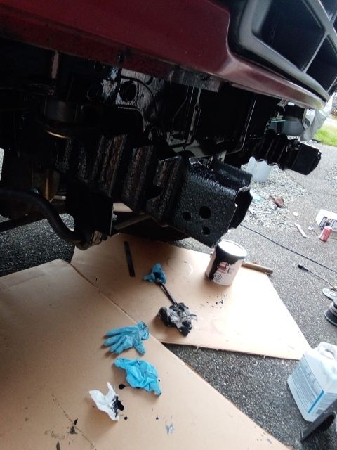 1994 Ford Bronco - Painting the frame and bumper area black with a can of paint and gloves on cardboard.