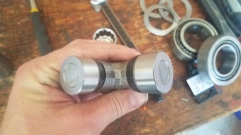 1985 Ford Bronco - Close-up of a universal joint with various bearings and tools visible on a workbench.