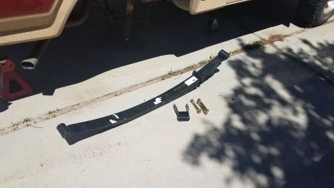 1985 Ford Bronco - Leaf spring and hardware removed from a vehicle, possibly for replacement or repair.