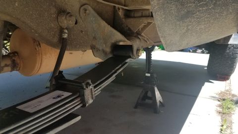 1985 Ford Bronco - The underside of a vehicle shows a leaf spring and exhaust system, with a tire visible in the background.