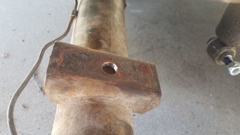 1985 Ford Bronco - Close-up of a rusty differential housing and brake line, with a bolt and nut visible on the right side.