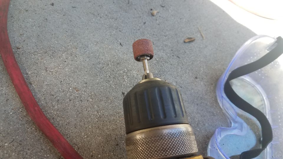 Drill with sanding drum and safety glasses on concrete