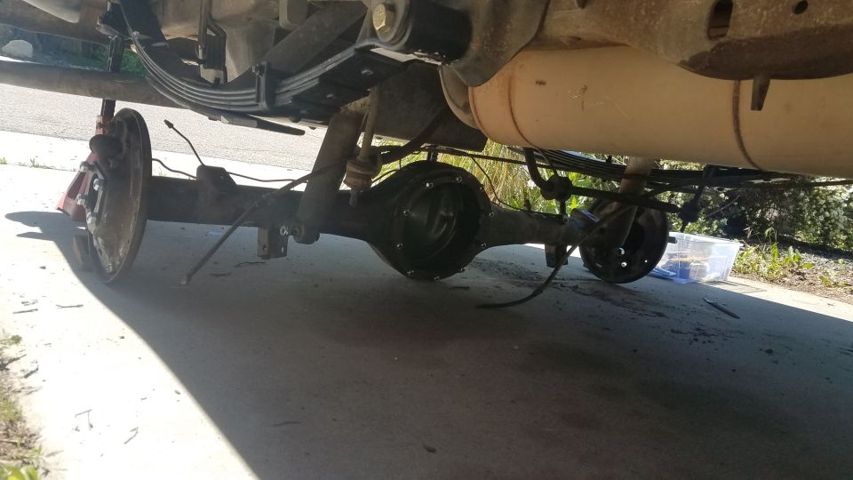 Underside view of a vehicle's rear axle, leaf springs, and brake drum assembly