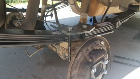 1985 Ford Bronco - Close-up view of a vehicle's rear axle leaf spring assembly, showing suspension components and a metal bracket.