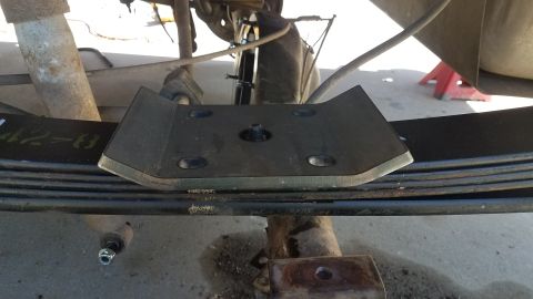 1985 Ford Bronco - A metal plate is attached to the leaf springs of a vehicle, likely for reinforcement or modification.