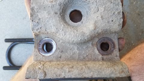 1985 Ford Bronco - Close-up view of a differential housing, showing mounting points and a U-shaped bracket, likely for a vehicle's drivetrain.