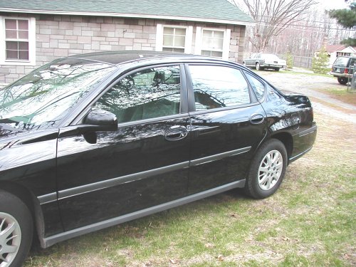 Side view of a black sedan parked on grass
