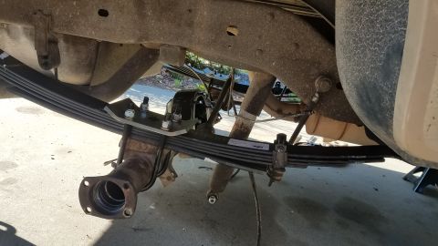 1985 Ford Bronco - Close-up view of the rear axle leaf spring suspension system, a Supermotors.net watermark.