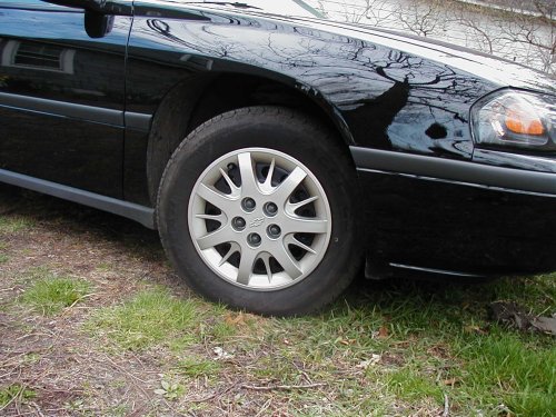 front corner of a black sedan, showing wheel and part of headlight