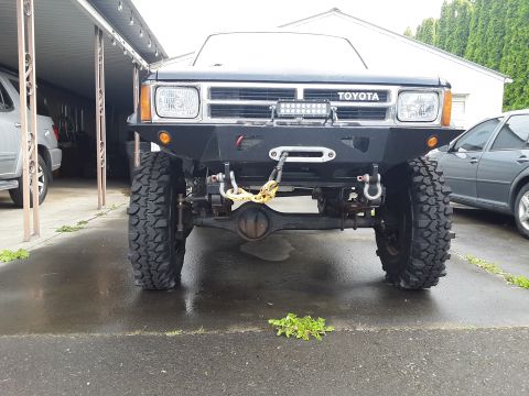 1985 Toyota Hilux - This modified Toyota truck features a custom bumper, winch, and off-road tires, suggesting it's built for terrain.