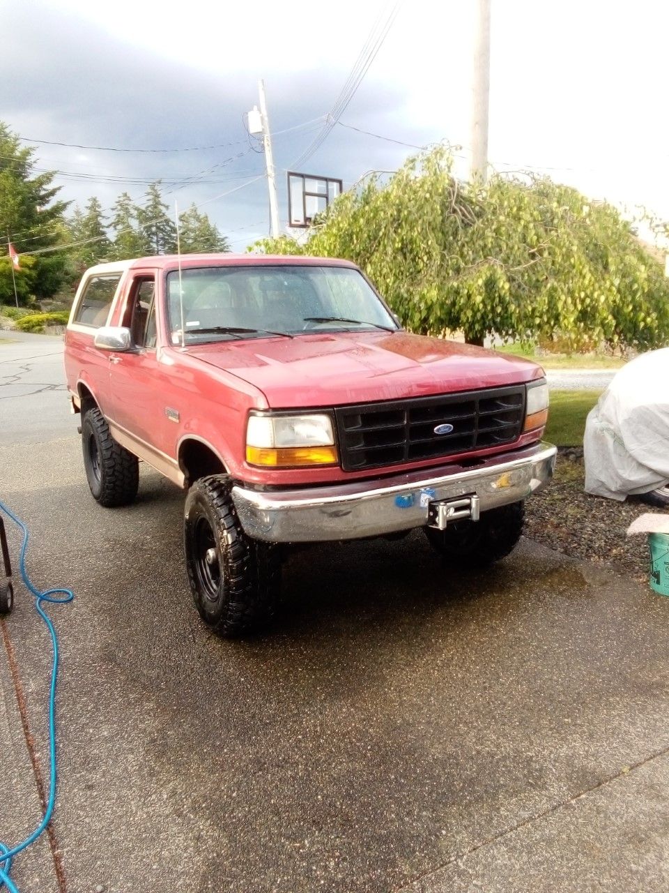 Red Ford Bronco with a white top, lifted, with aftermarket bumper and winch