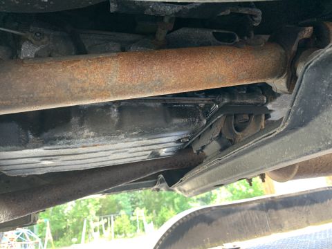 2000 Jeep Cherokee - The underside of a vehicle reveals rusted exhaust components and a transmission pan, with a partial view of a tire and Supermotors logo.