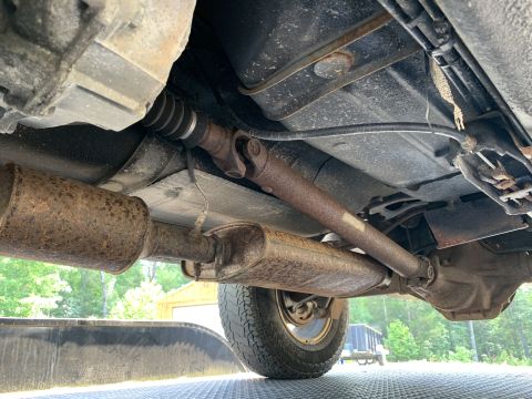 2000 Jeep Cherokee - The underside of a vehicle is visible, the driveshaft, exhaust components, and a rear wheel.